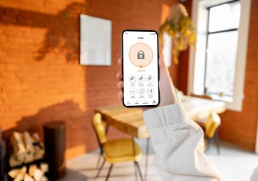 Woman holding phone while accessing smart home application.